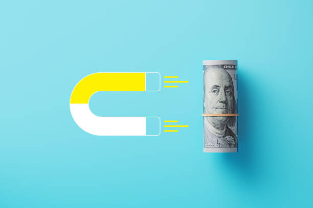istock Rolled US Dollar Gravitated Toward A Yellow Magnet On Blue Background 2160457710