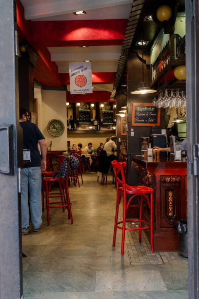 Seville, Spain. February 5, 2024 - Red bar stools and customers in a traditional Spanish Restaurant