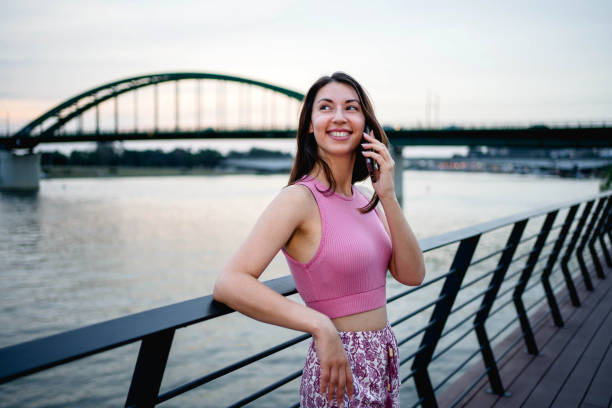 istock Young woman talking on the phone by the riverside 2160461321