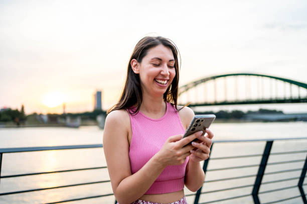 istock Young woman using phone by the riverside 2160461597