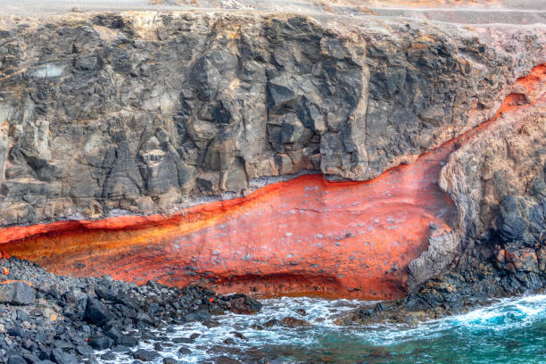 Cliff with a red flow of water running down it. Majestic rock formation overlooking the ocean