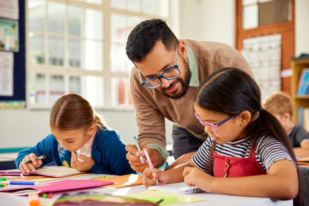 istock Teacher helping schoolchildren during lesson in classroom 2160473936