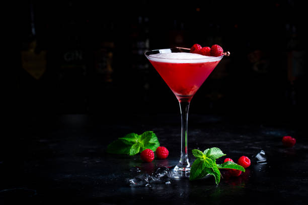 istock Summer red  cocktail with gin, raspberry syrup, lime juice, quail egg white and ice in glass. Black bar counter background 2160473967
