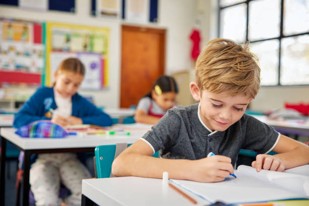 istock Focused schoolchildren writing in notebook during lesson at school 2160473978