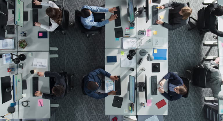 Top Down View Of Diverse Colleagues Working In Corporate Office Of Law Firm. Using Desktop Computers, Discussing Documents, Analyzing Data. Concept Of Teamwork And Professional Business Environment.