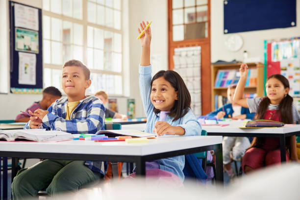 istock Girl raising hand in classroom: she knows the answer! 2160474564