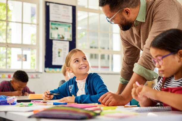 istock Happy little girl asks teacher for help in elementary classroom 2160474582