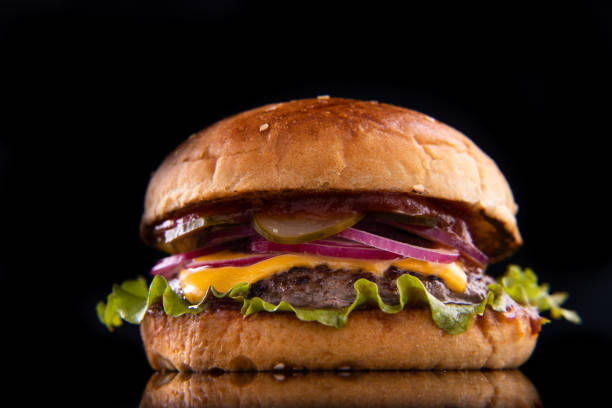 istock Burger with beef, cheese, vegetables on black plate. Dark Background. Close up. 2160475329