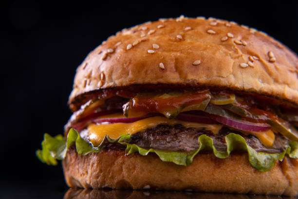 istock Burger with beef, cheese, vegetables on black plate. Dark Background. Close up. 2160475406