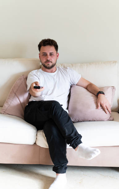 istock Man watching TV on the sofa during the day 2160475681