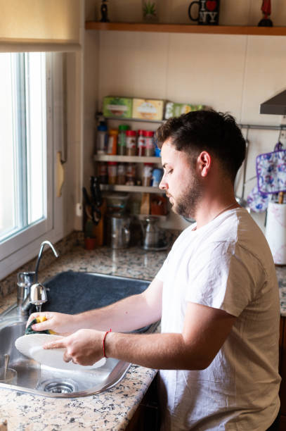istock Man cleaning dishes at home 2160475717