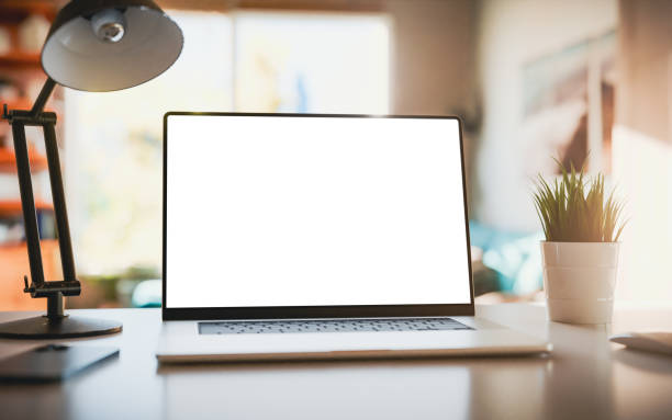 istock Laptop with a blank screen on a table in a bright home office. Perfect for inserting your own content. 2160476328