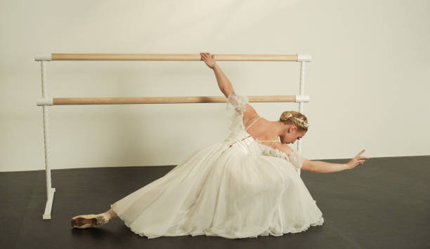 istock Ballet Dancer Stretching at Barre in Flowing White Dress 2160478704