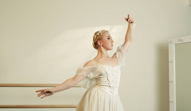 istock Ballet Dancer in White Dress Practicing at Barre in Sunlit Studio 2160479051