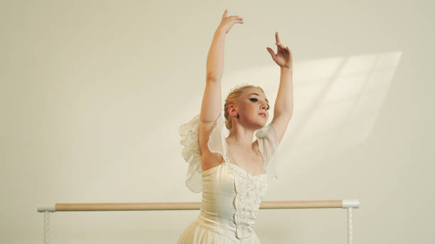 Ballet Dancer in Uplifted Pose at the Barre in Sunlit Studio