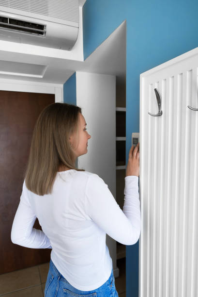 istock Woman controls an air conditioner from a remote control on the wall. 2160488857
