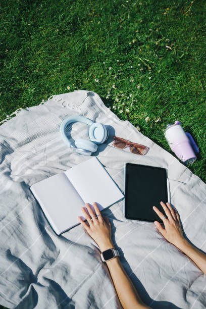 istock Top view of woman’s hands with a digital tablet and open note pad on a blanket 2160496772