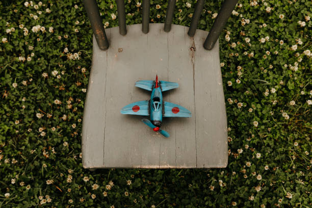An antique, toy airplane on a wooden chair.