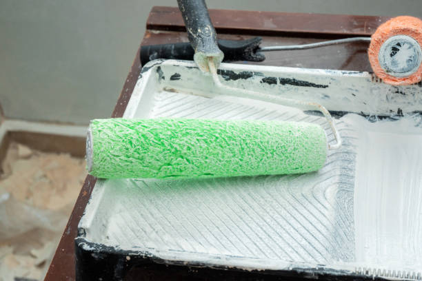 Paint roller with painting equipment and white paint on table at home, copy space