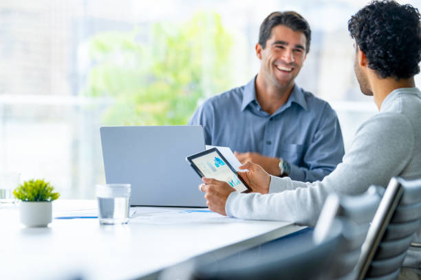 istock Two businessmen working on a digital tablet and laptop computer in the office. 2160504111