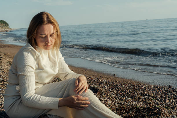istock Woman Sitting on Beach Next to Ocean 2160505174