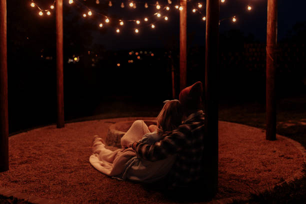 istock Couple cuddling under fairy lights at night 2160509381