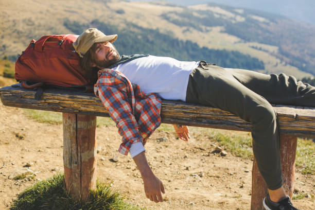 Senior man laying down in the meadow, relaxing after hiking