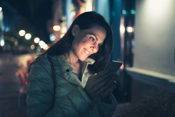 istock Smiling Woman Using Smartphone at Night 2160514203
