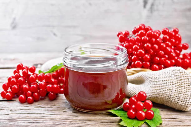 basket with red currant on table and spoon filled with sugar as well as a currant jam glass jar.