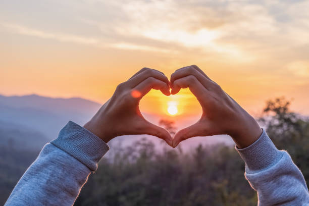 istock hands in shape of love heart sunset background 2160522853
