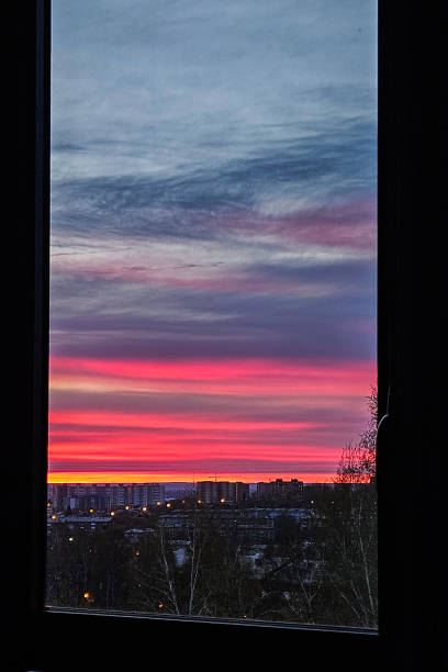 city sunset landscape nature view from a window background from. Sunset over rooftops with building lights. Selective focus.