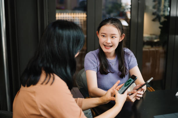 istock Daughter teaching mother how to use to access a restaurant menu. 2160528683