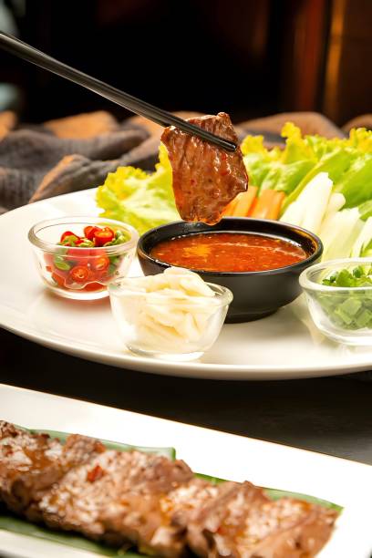 Spicy chili sauce drenched beef held by chopsticks