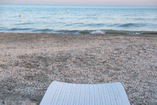 A single white sun lounger on the beach facing the sea