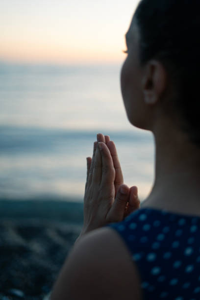 istock Young woman meditating on the beach at sunset 2160544136