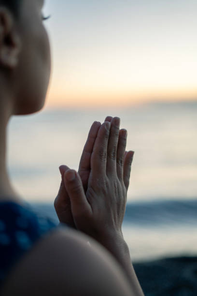 istock Young woman meditating on the beach at sunset 2160544137