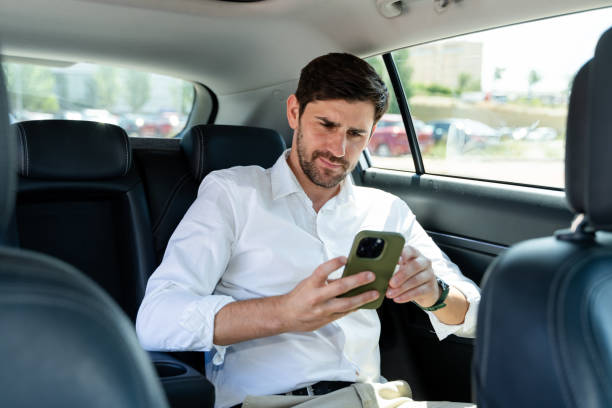 istock Businessman sitting in car back seat using smartphone 2160545558