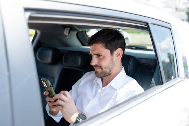 istock Businessman using smartphone while sitting on backseat of car 2160545584