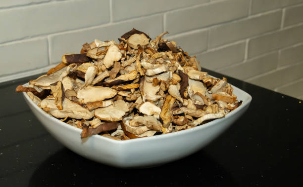 Dried mushrooms in a white bowl on a black kitchen table.