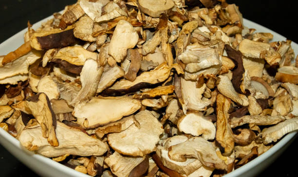 istock Dried mushrooms in a white bowl on a black kitchen table. 2160548388