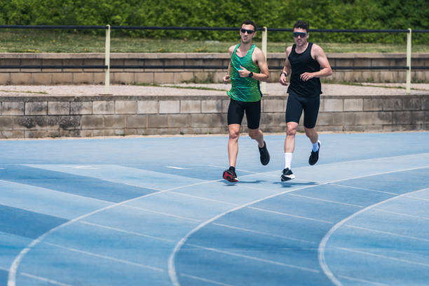 istock Two men with sunglasses running on a blue track 2160551217