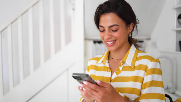 istock Cheerful woman using her smartphone at home 2160551253