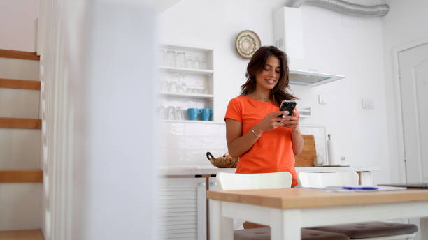 Cheerful woman using her smartphone at home