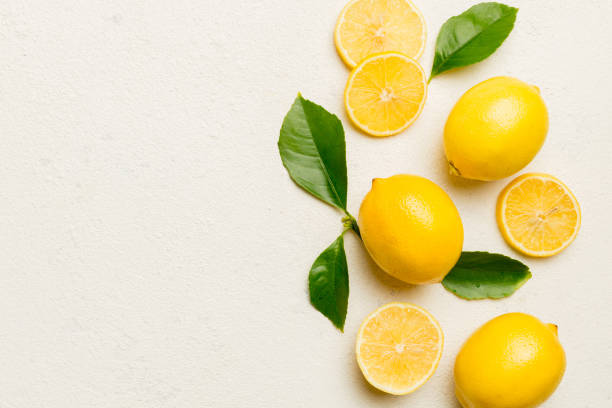 istock Many fresh ripe lemons with green leaves on colored background, top view, space for text 2160558004