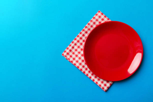 istock Top view on colored background empty round red plate on tablecloth for food. Empty dish on napkin with space for your design 2160558068