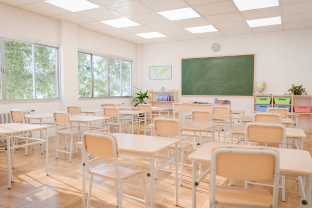 Bright and spacious classroom with large windows, green chalkboard, and multiple desks arranged neatly. Concept of education and learning. 3d rendering