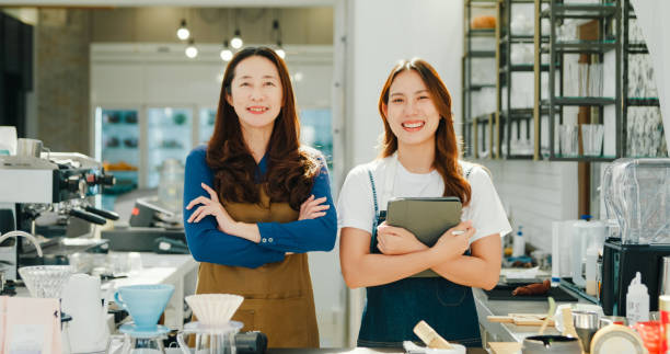 istock Two happy female entrepreneurs, a mentor and her trainee, pose with confidence at their successful and sustainable coffee shop. Small business owner. 2160561664