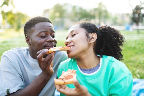 istock Young black couple eating pizza at sunset 2160563204