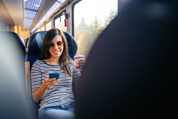 istock Young Woman Drinking Coffee And Using A Phone While Riding In A Train Through Lubeck In Germany 2160567545