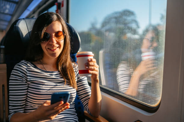 istock Young Woman Drinking Coffee And Using A Phone While Riding In A Train Through Lubeck In Germany 2160567557
